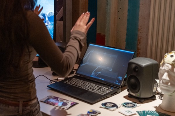 An einem Mitmachstand steuert eine Besucherin mit Handbewegungen eine Visualisierung auf einem Laptop.